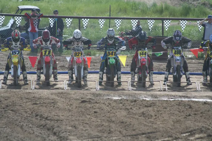 Motocross riders lined up behind the starting gates at Temple Hill.